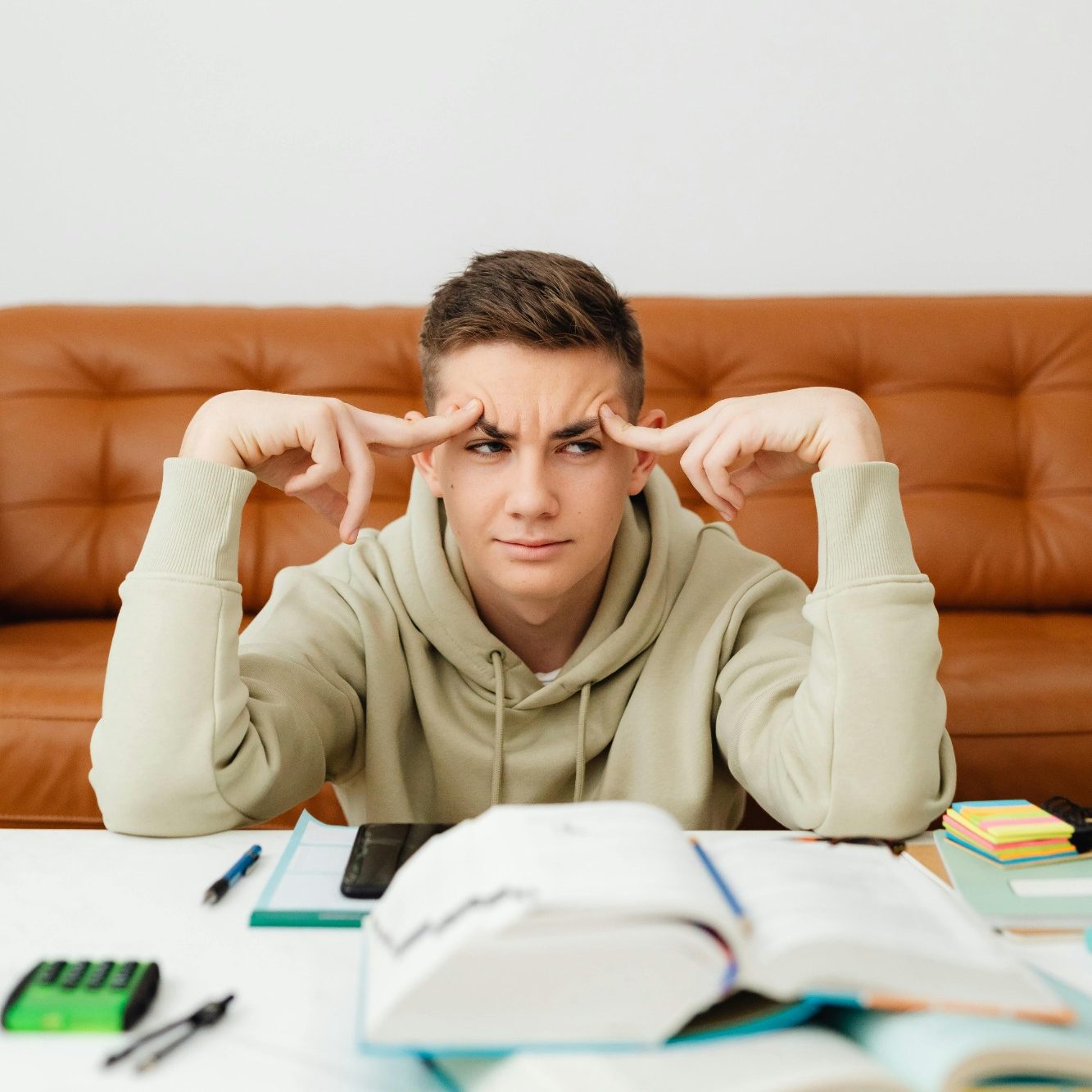 Jeune homme stressé en train d'étudier, entouré de livres et de notes.